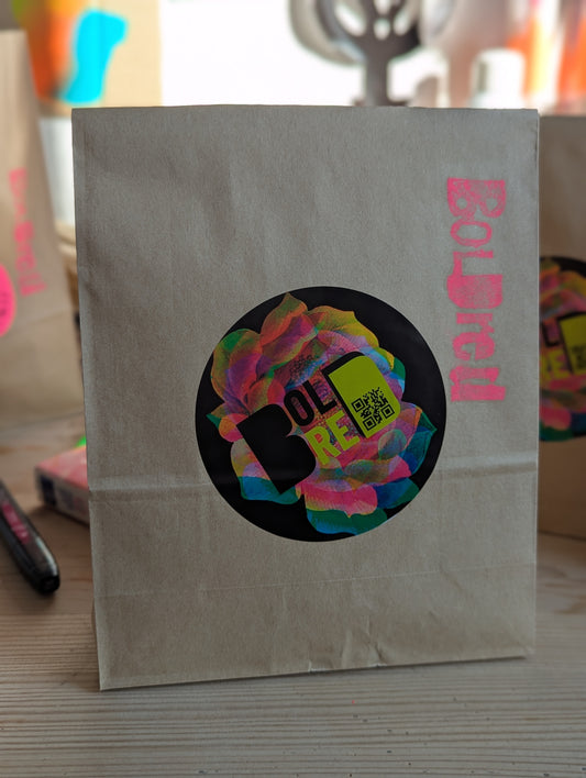 Packaging of the DIY kit with a pink BOLDred logo printed on the side and a BOLDred sticker decorating the paper bag