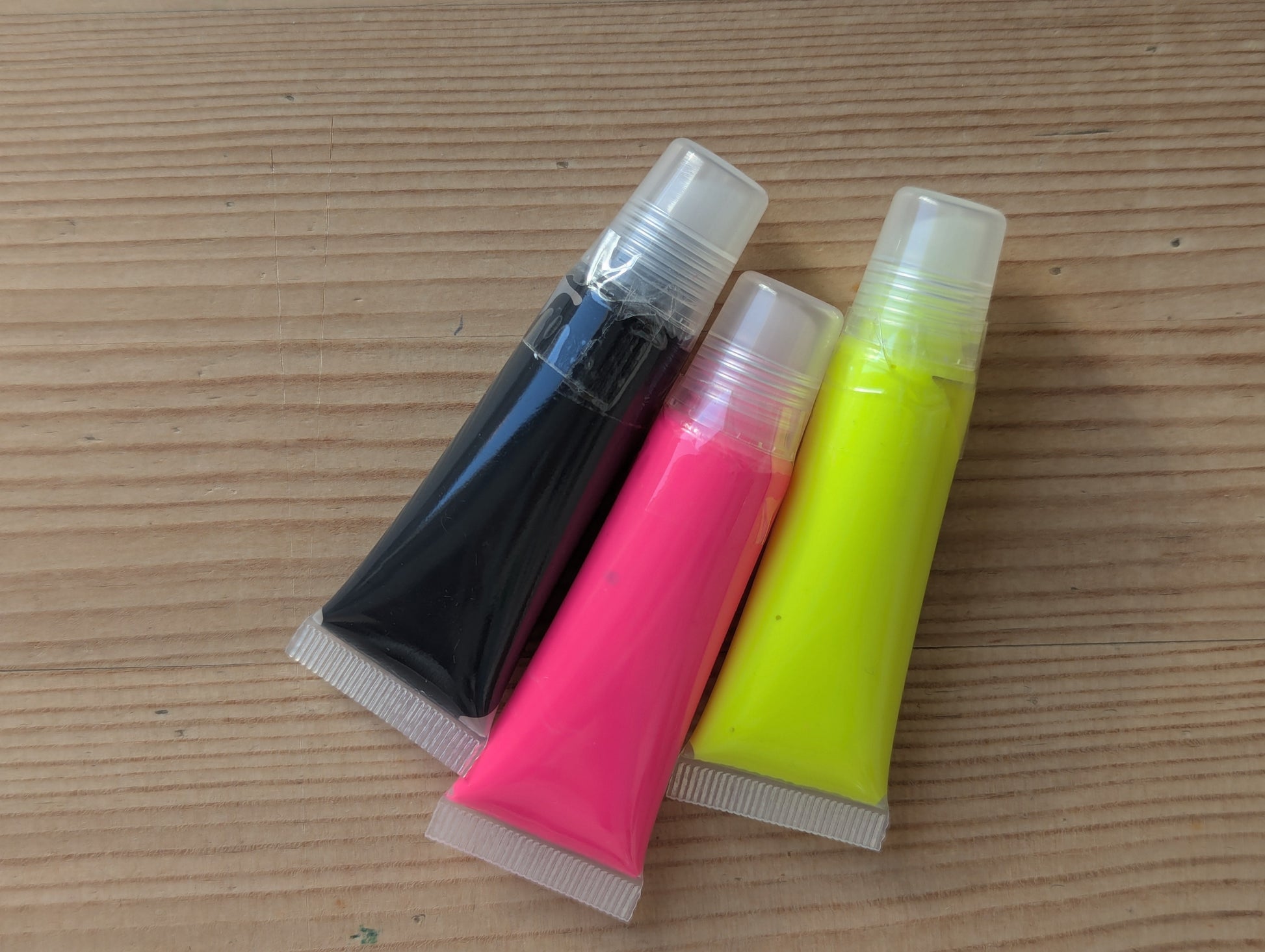 Three paint tubes. Neon pink, neon yellow, black 