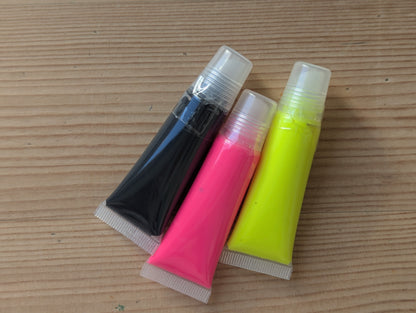 Three paint tubes. Neon pink, neon yellow, black 