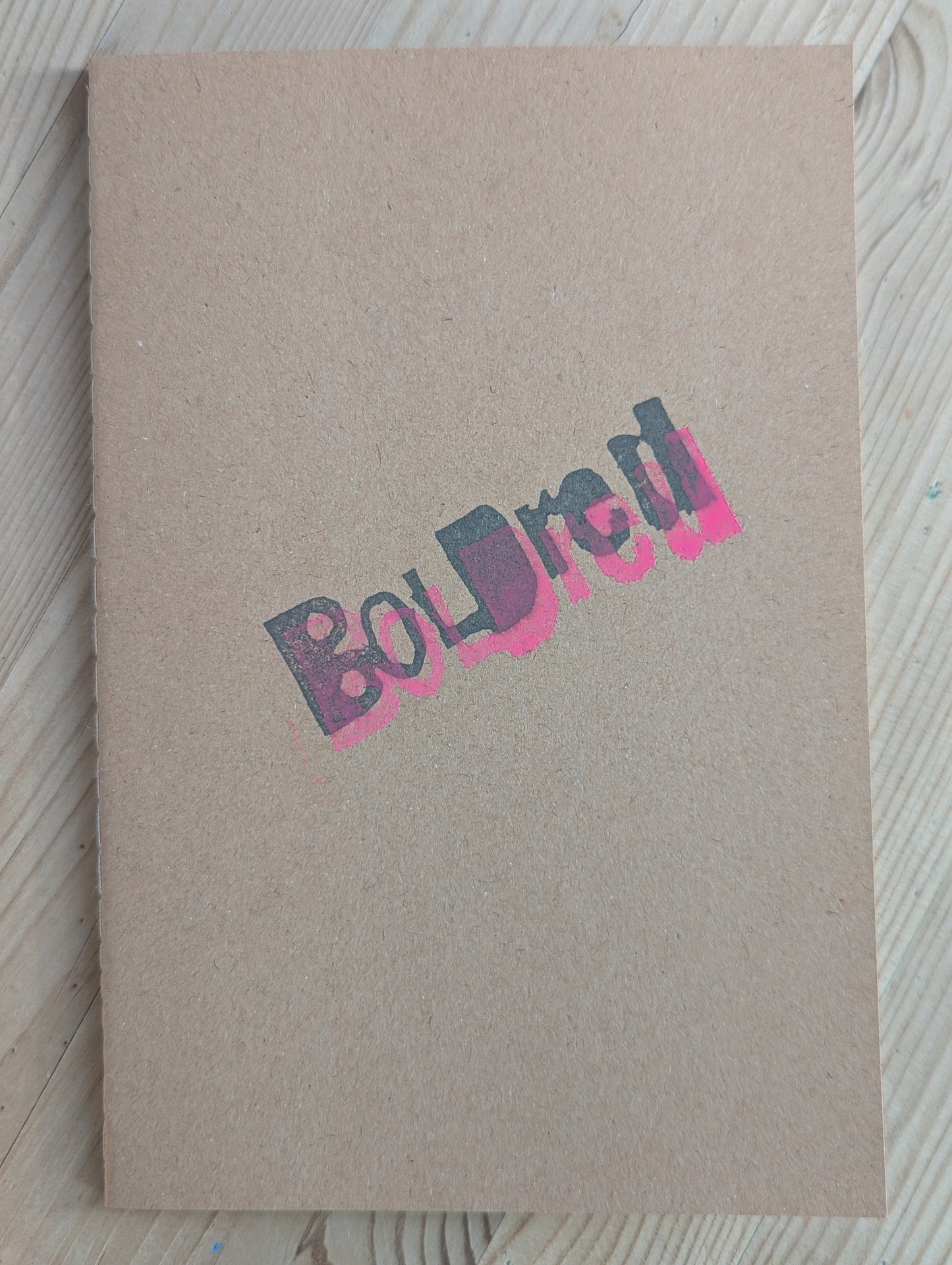 Brown A5 Notebook with brown blank paper with the BOLDred stamp in black and pink places on top of each other 