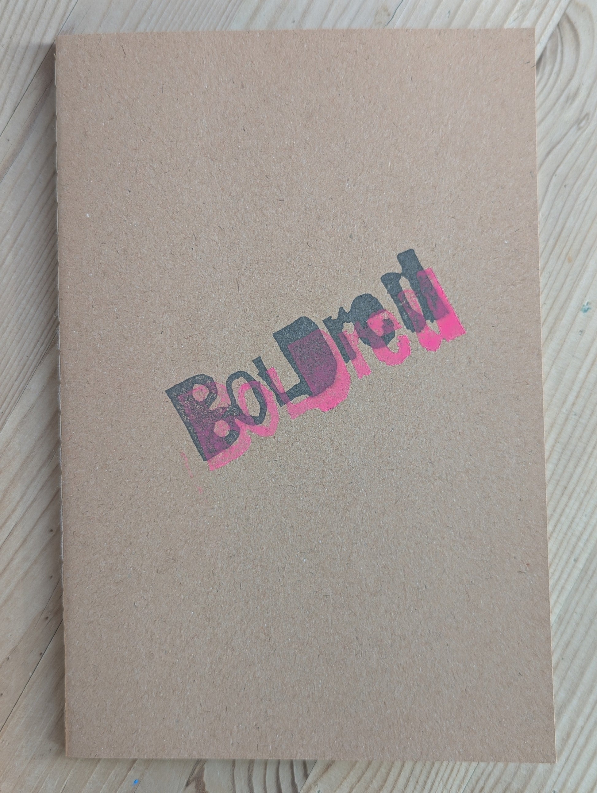 Brown A5 Notebook with brown blank paper with the BOLDred stamp in black and pink places on top of each other 